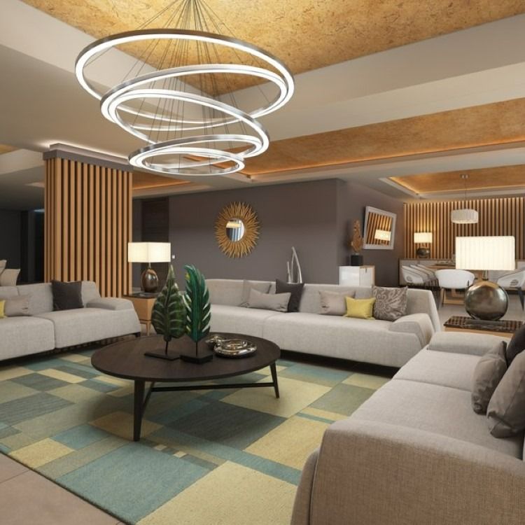 Modern living room with neutral couches, patterned rug, and a large circular chandelier.