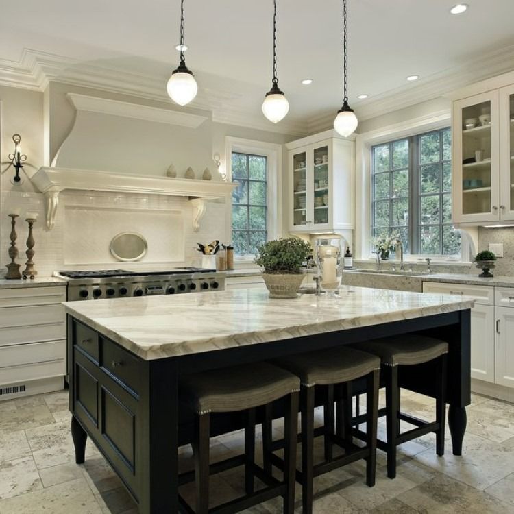 Kitchen with black island, marble countertop, pendant lights, and white cabinets.