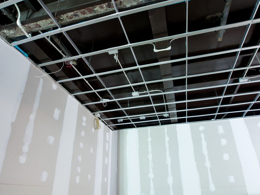 Metal grid ceiling framework installed, with unfinished drywall walls visible below.