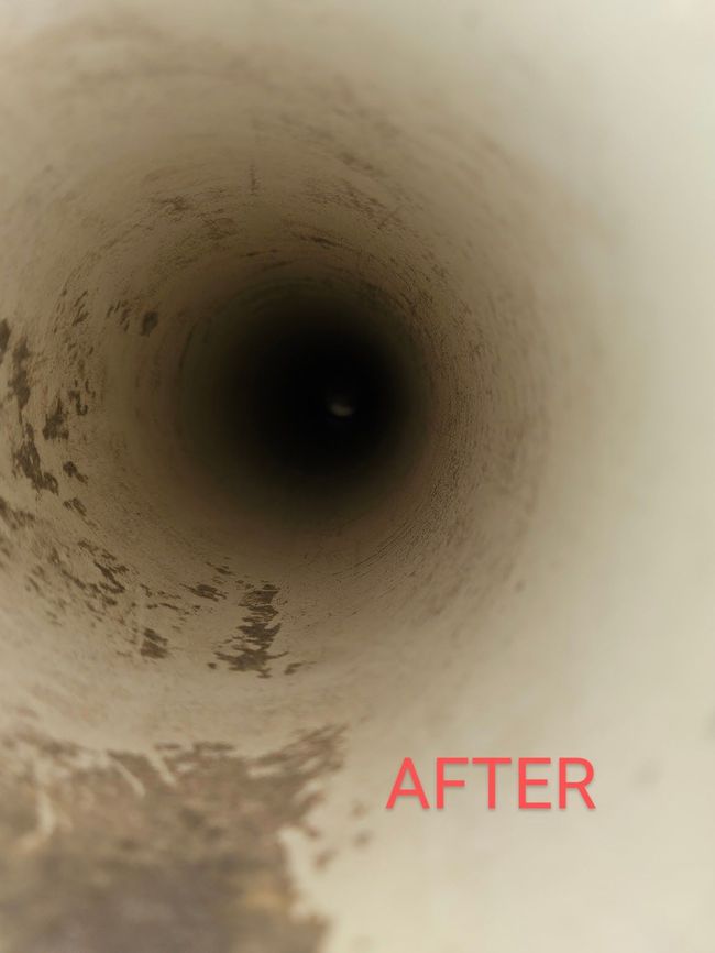 Inside view of a white pipe, mostly clean with a dark opening in the center.