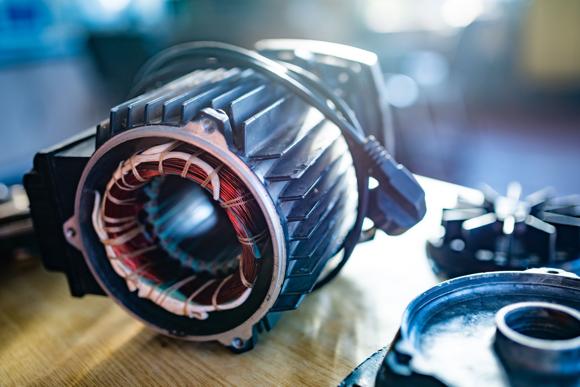 Electric motor components on a wooden surface, showing copper windings and metal casing.