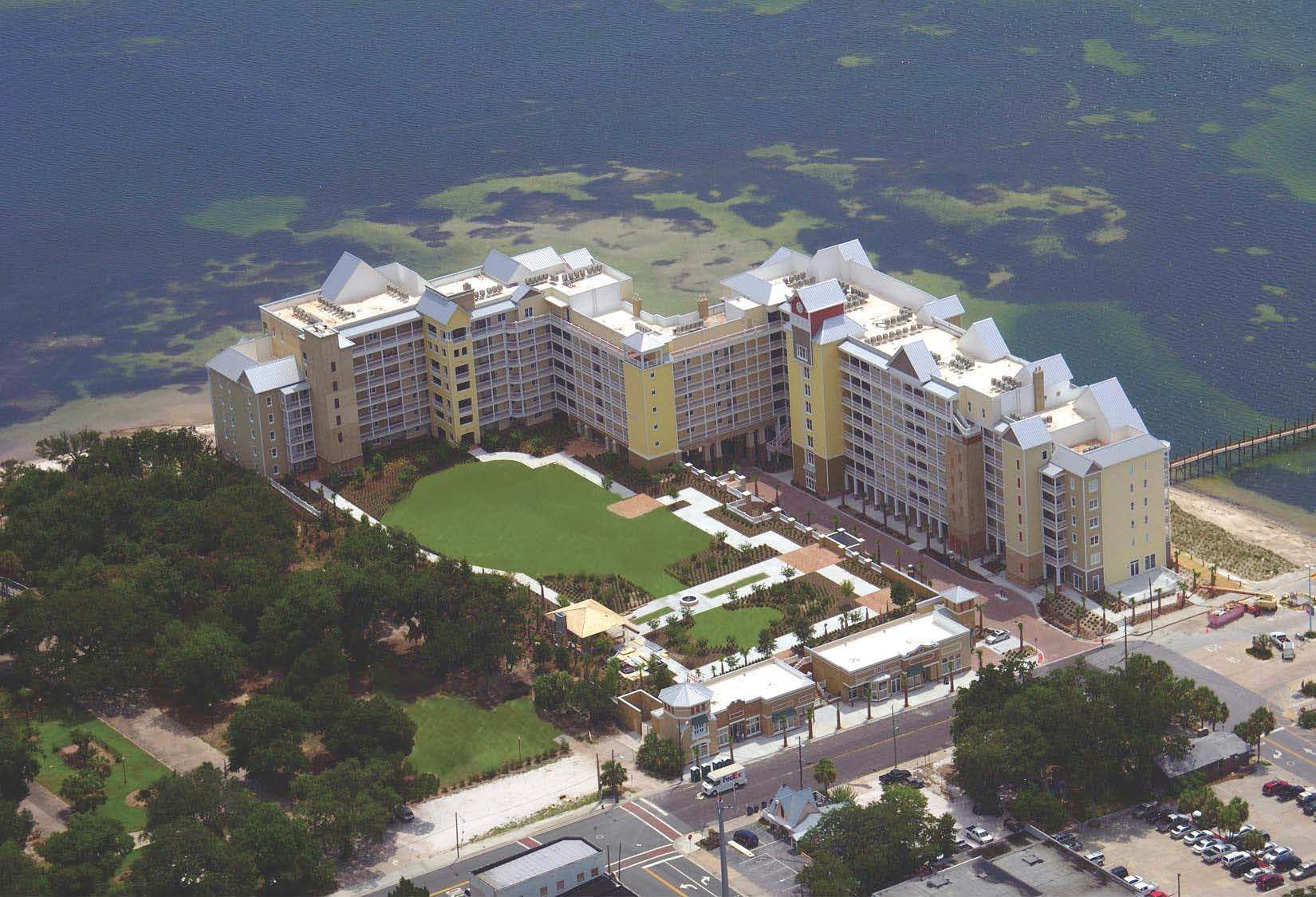 White church with steeple surrounded by trees, cloudy blue sky.