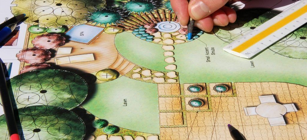 Hand drawing on a landscape plan with a ruler and colored pencils, with green and tan design elements.