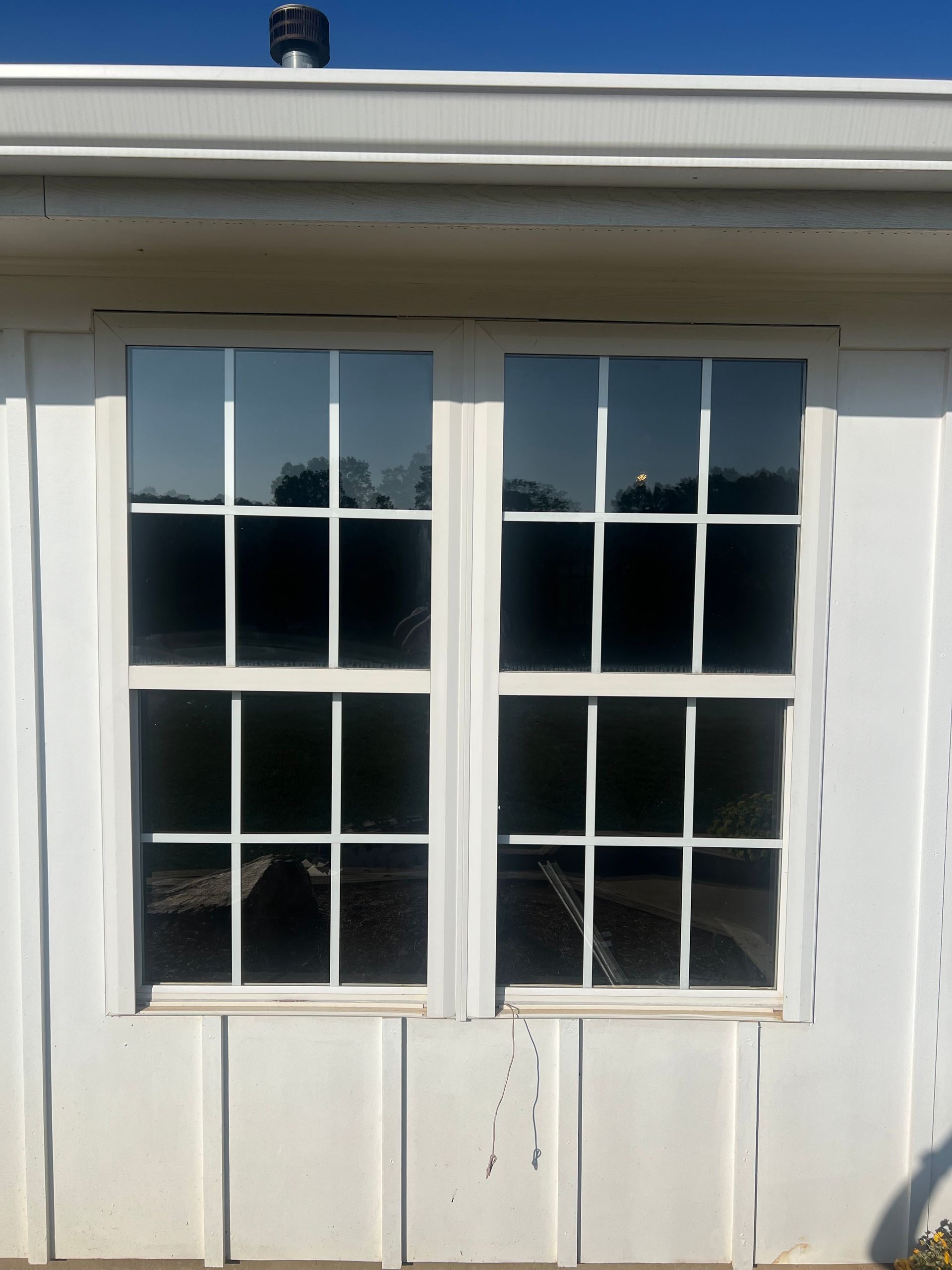 A white house with two windows and a chimney on the roof
