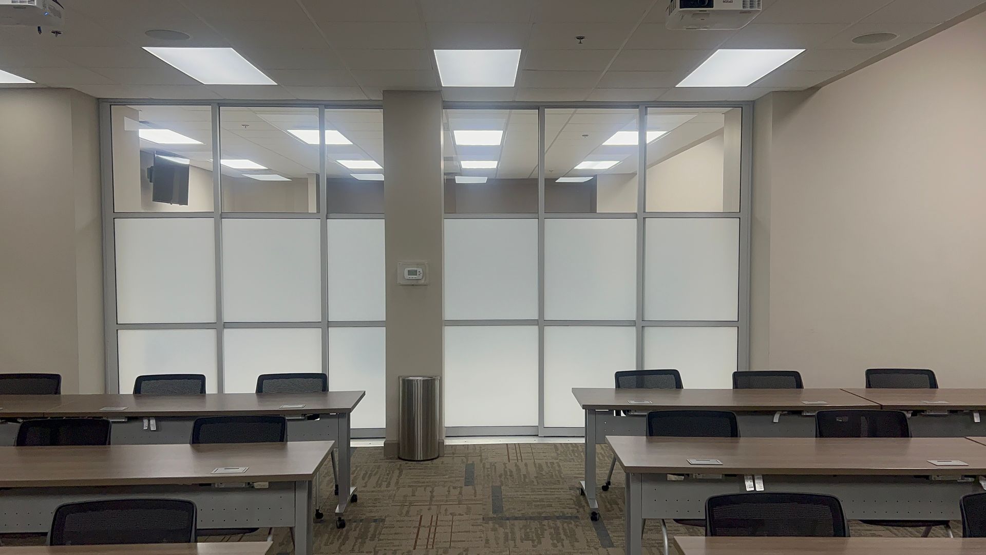 A classroom with tables and chairs and a projector