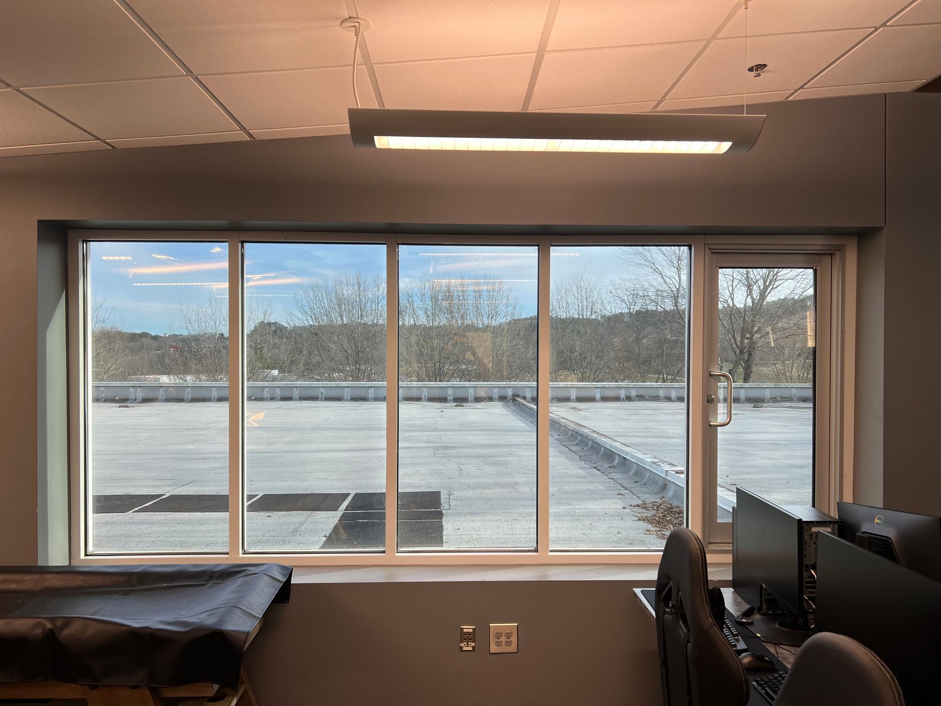 A large window in an office with a view of a parking lot.