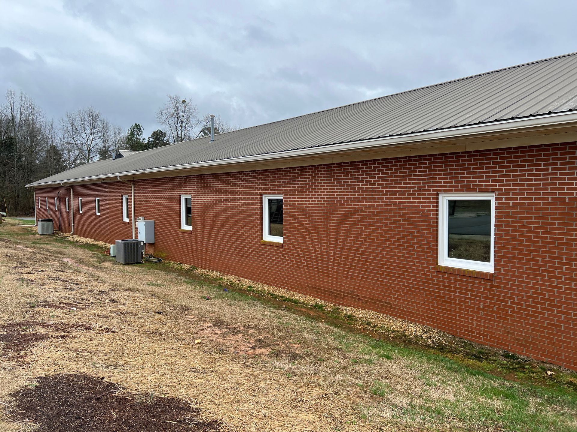 A brick building with a metal roof and a lot of windows.