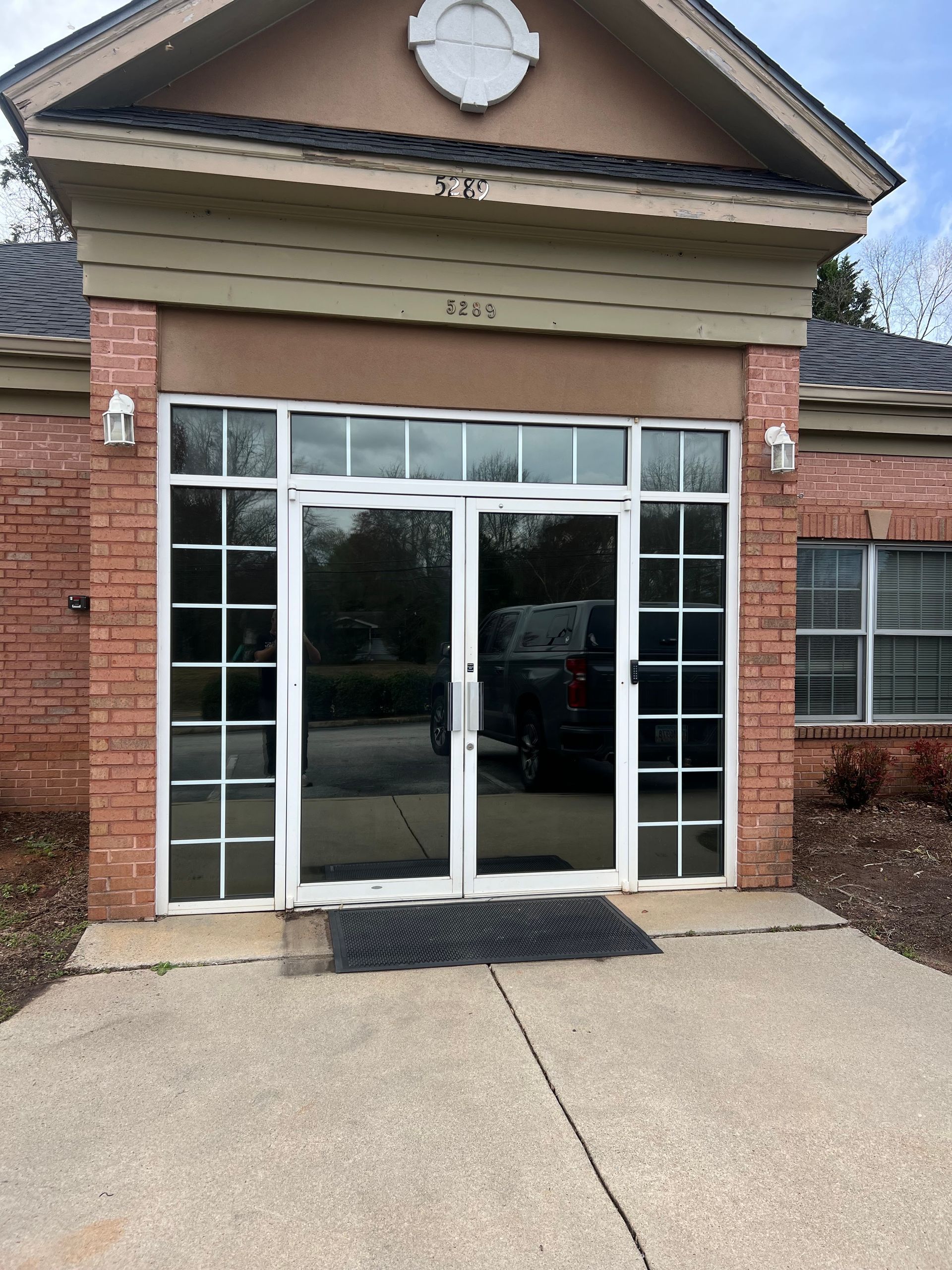 A brick building with a white door and a clock on top of it.