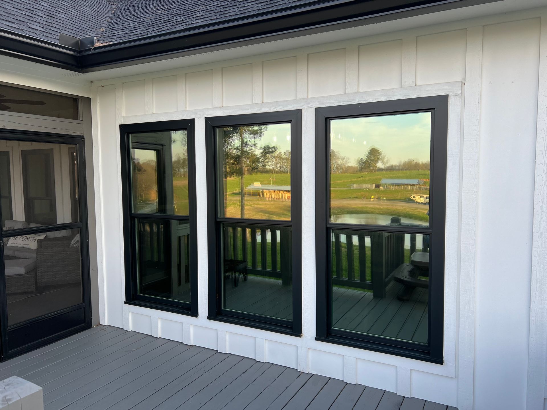 A white house with black windows and a deck.