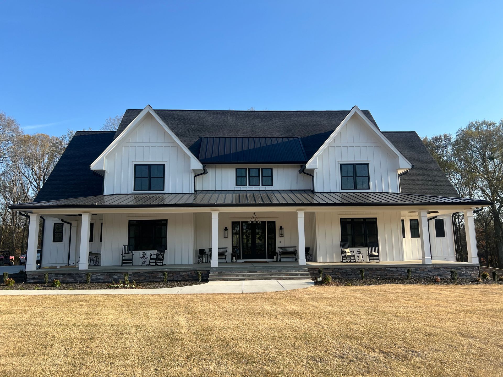 A large white house with a black roof and a large porch.