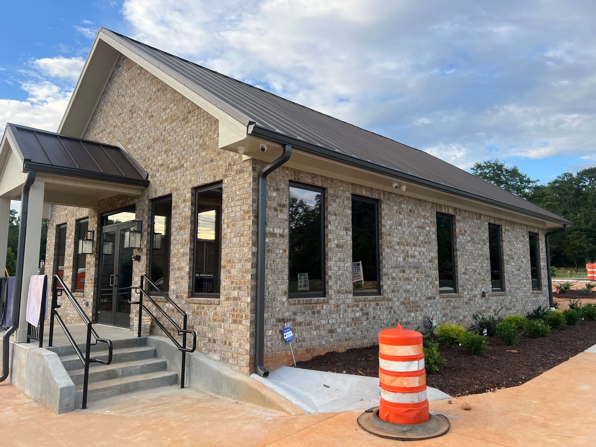 A large brick building with stairs and a traffic cone in front of it.