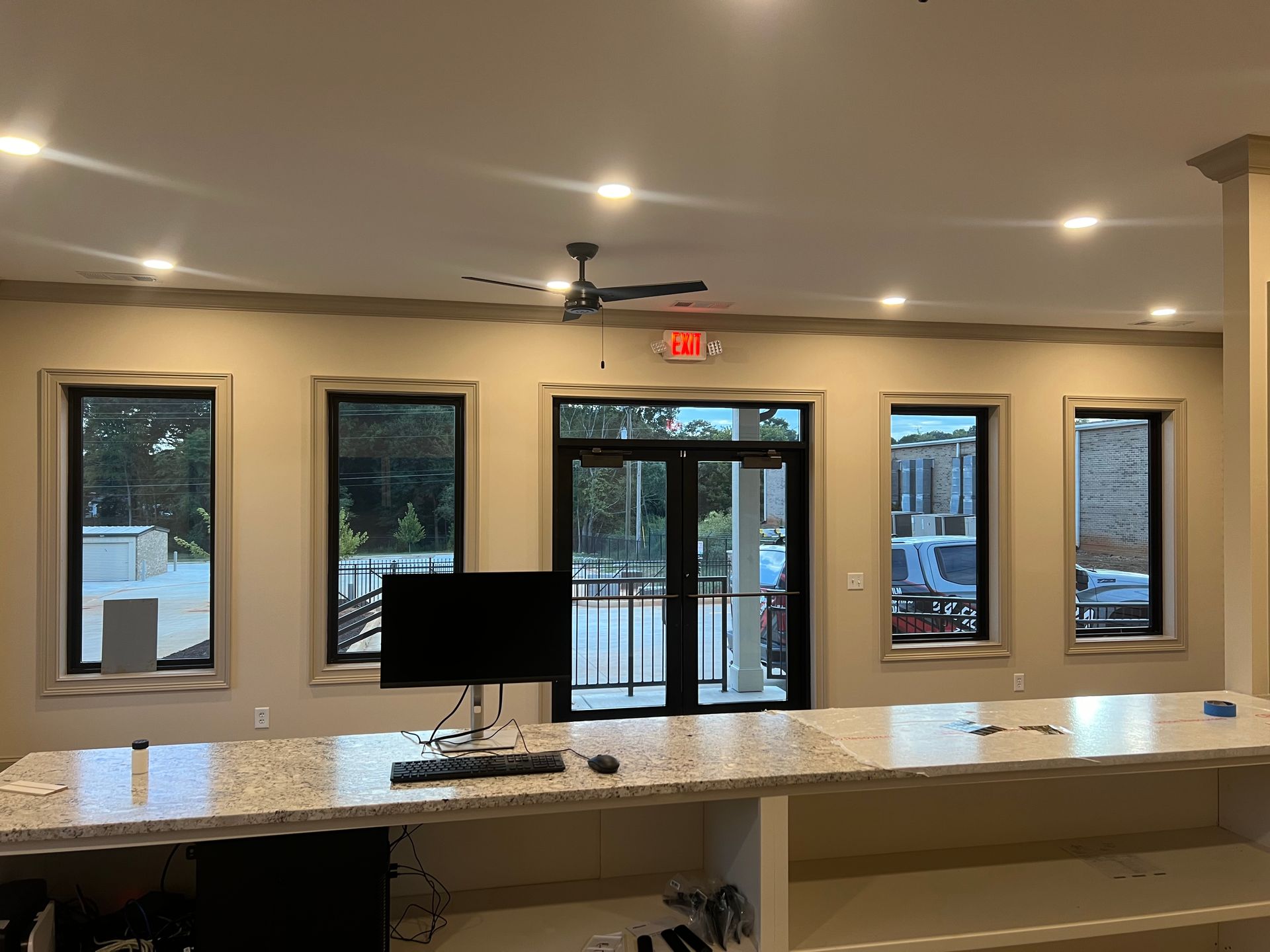 A room with a ceiling fan and a computer on a counter