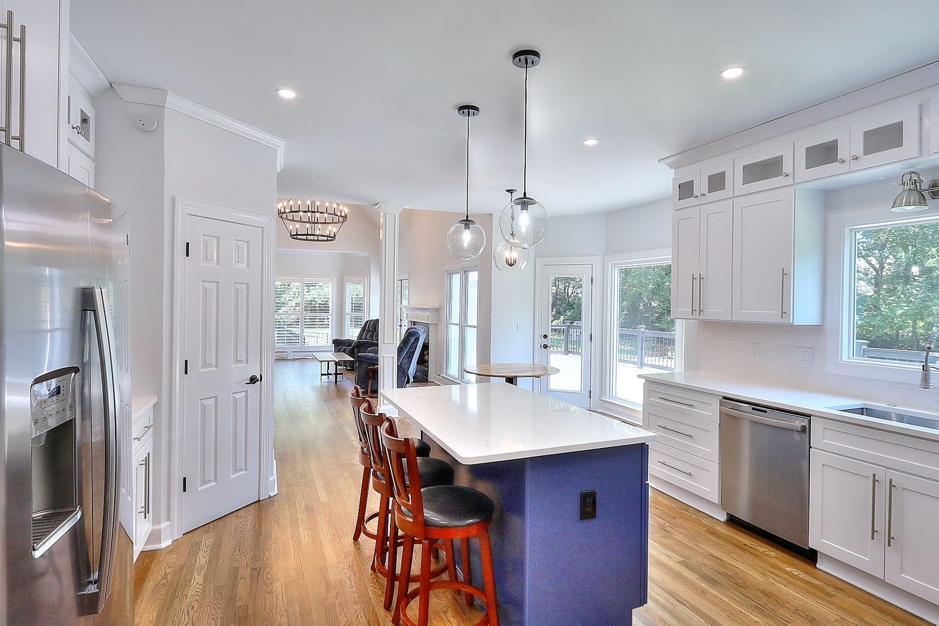 A kitchen with white cabinets , stainless steel appliances , and a large blue island.