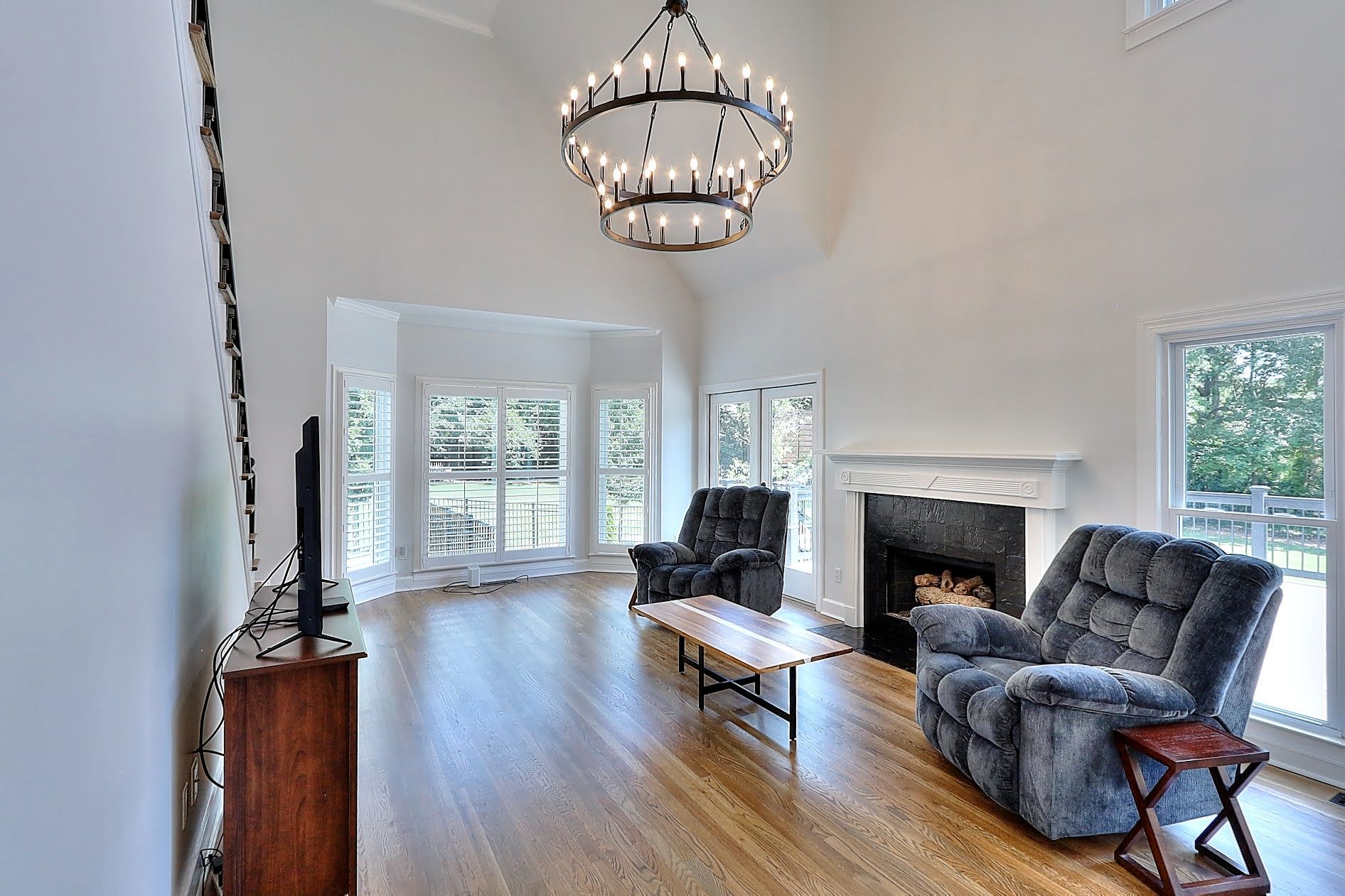 A living room with hardwood floors , a fireplace and a chandelier.
