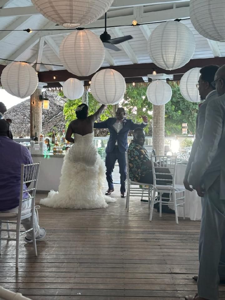 Bride and groom dancing at wedding reception under white paper lanterns.