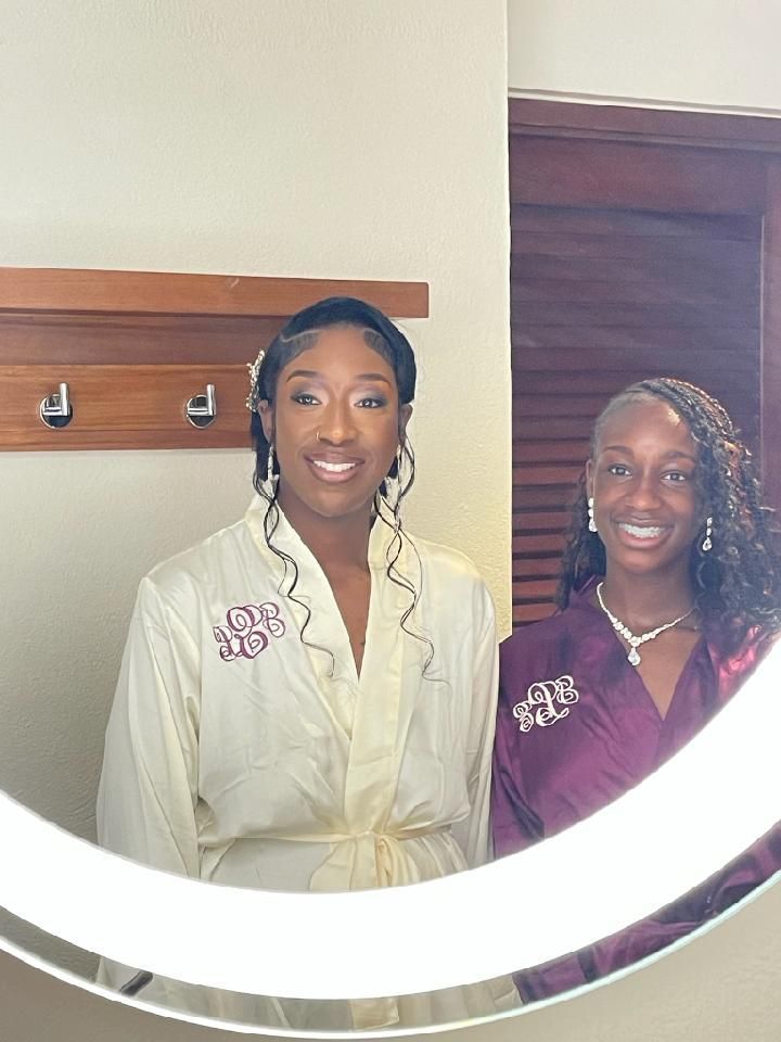 Two smiling women in robes pose in a mirror. One wears cream, the other maroon.