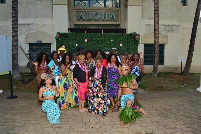 A group poses in front of a green hedge with an 