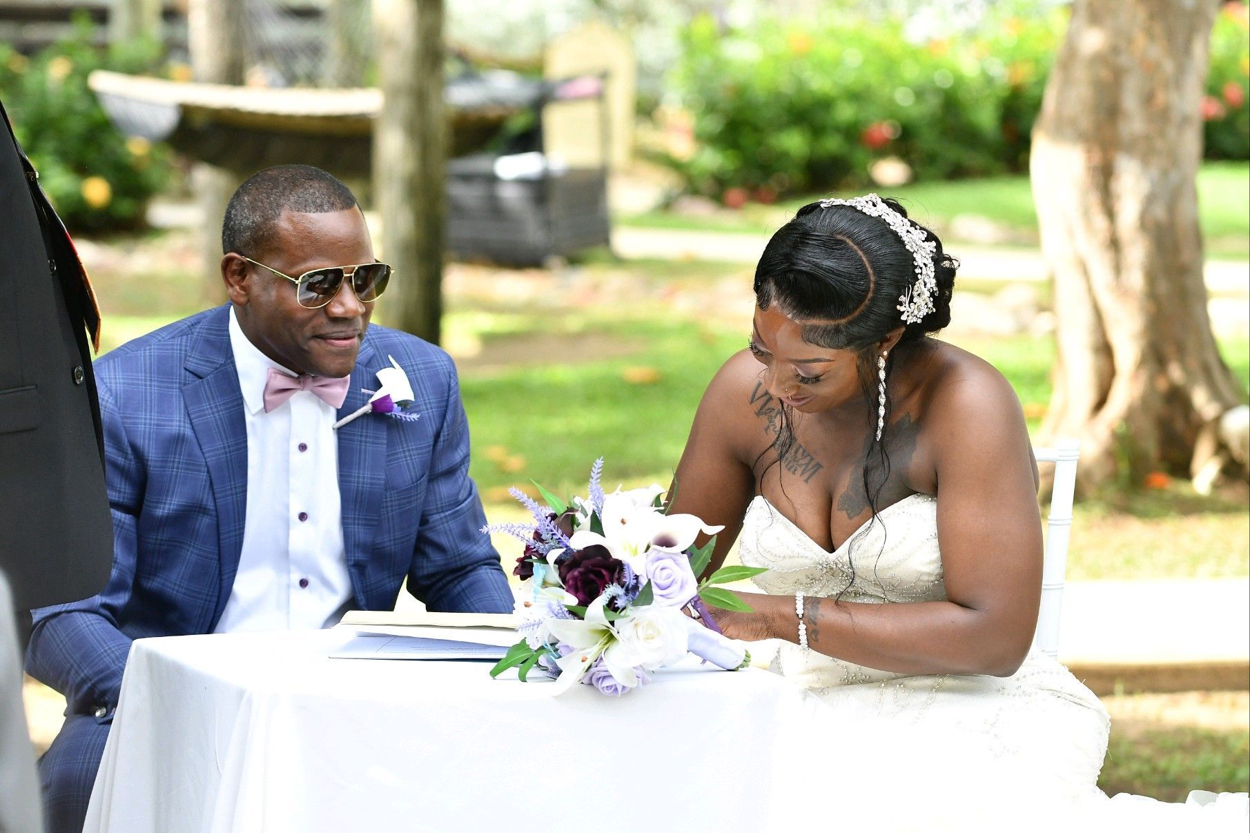 Bride and groom signing marriage certificate at outdoor ceremony.