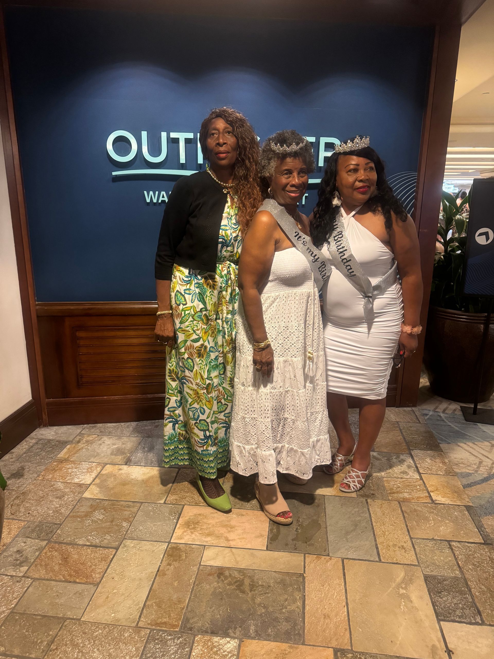 Three people pose together in front of a blue 