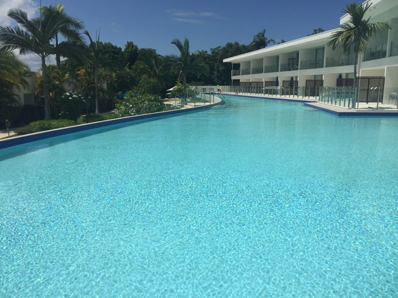 Pool With Clear Turquoise Water Next to a White Hotel Building — Dean Thomas Pools in Manunda, QLD