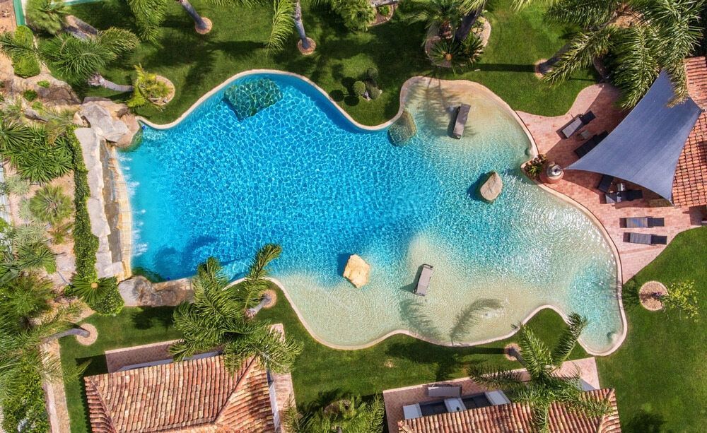 Aerial View of a Freeform Swimming Pool With a Sandy Beach Area — Dean Thomas Pools in Mission Beach, QLD