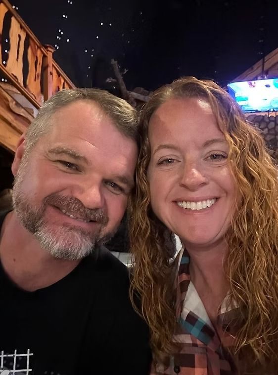 A man and a woman are posing for a picture together and smiling.