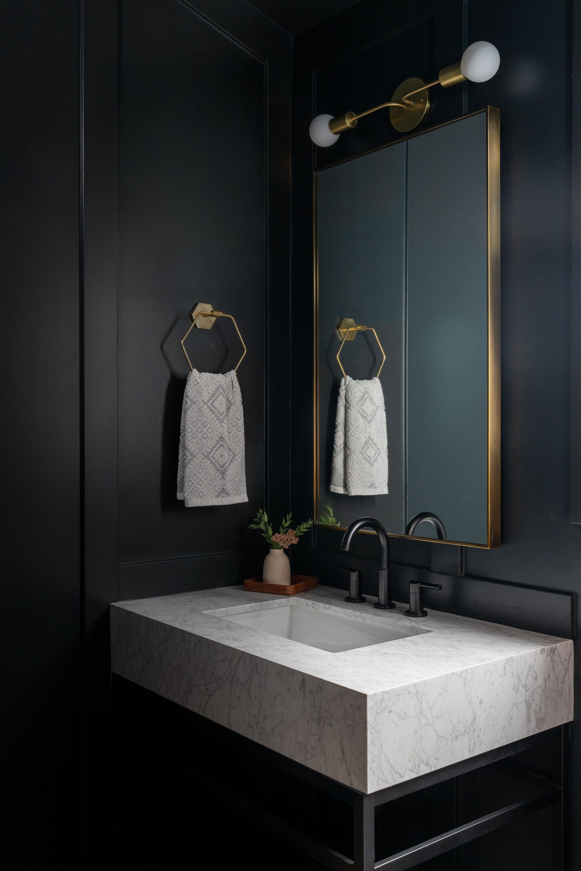 A bathroom with black walls , a sink and a mirror in Seattle, WA.