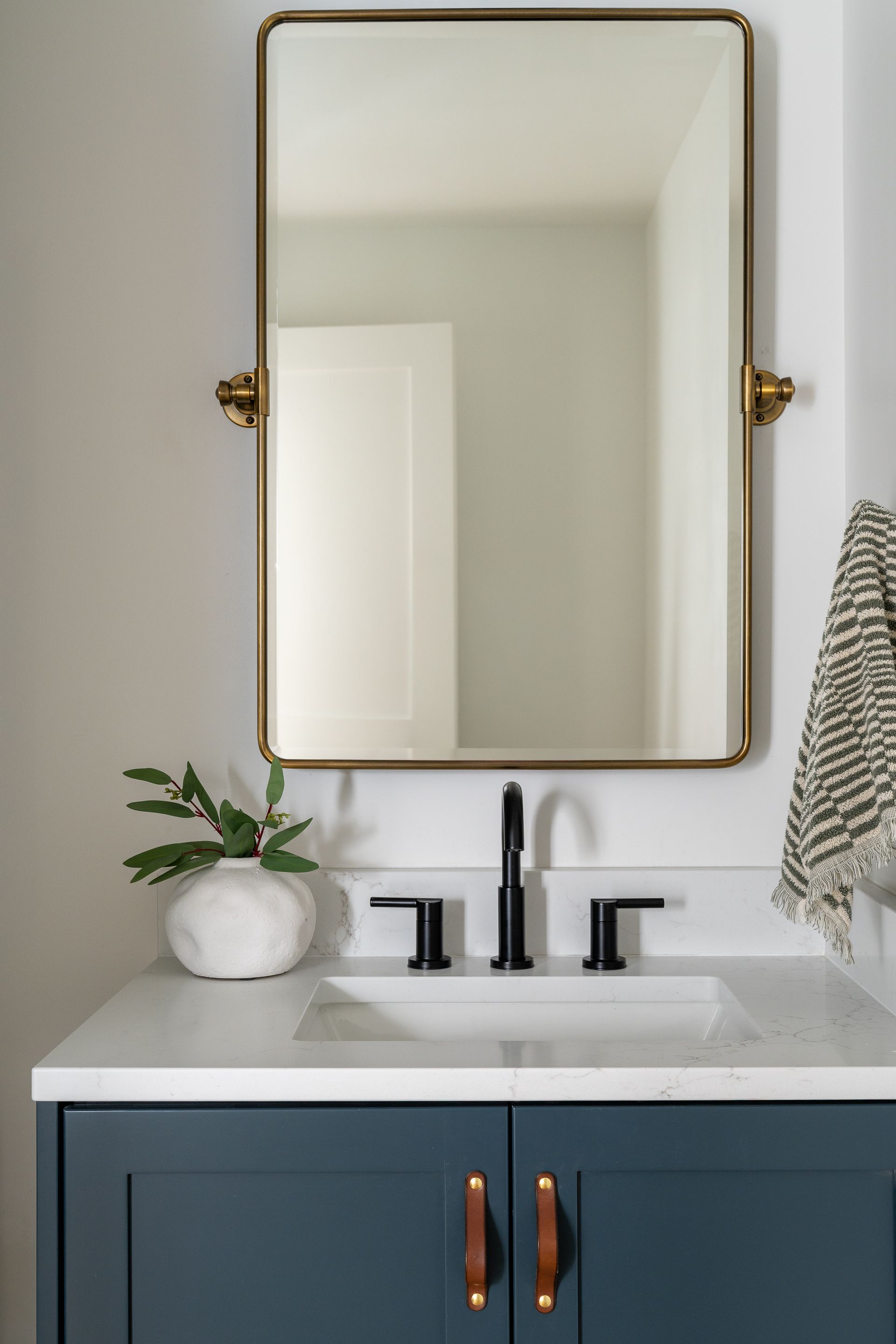 A bathroom sink with a mirror and a plant in Seattle, WA. Allison Myers Design. Emily Barrows Photography. 