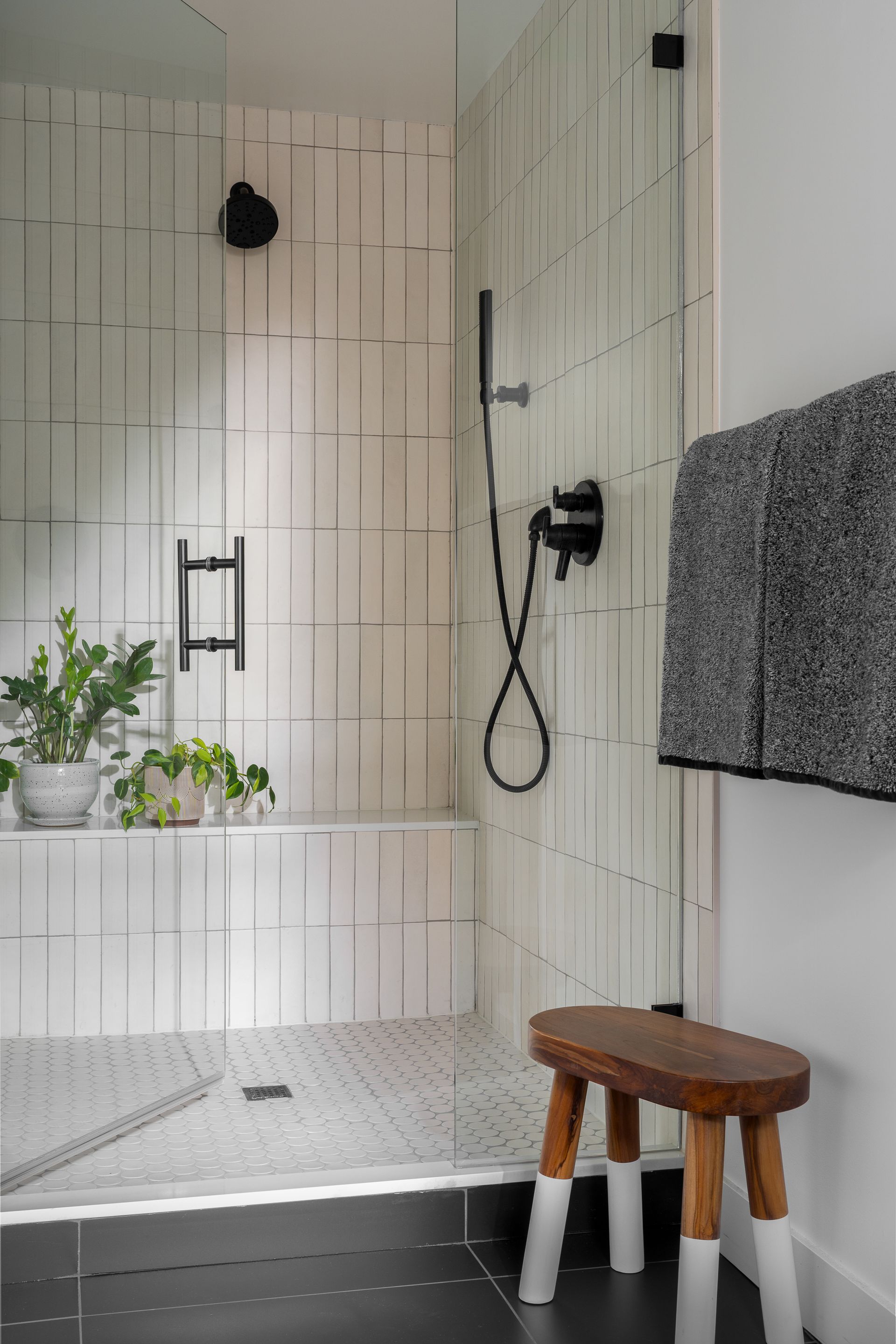 A bathroom with a walk in shower and a wooden stool. Seattle, WA. Emily Barrows Photography. Allison Myers Design.