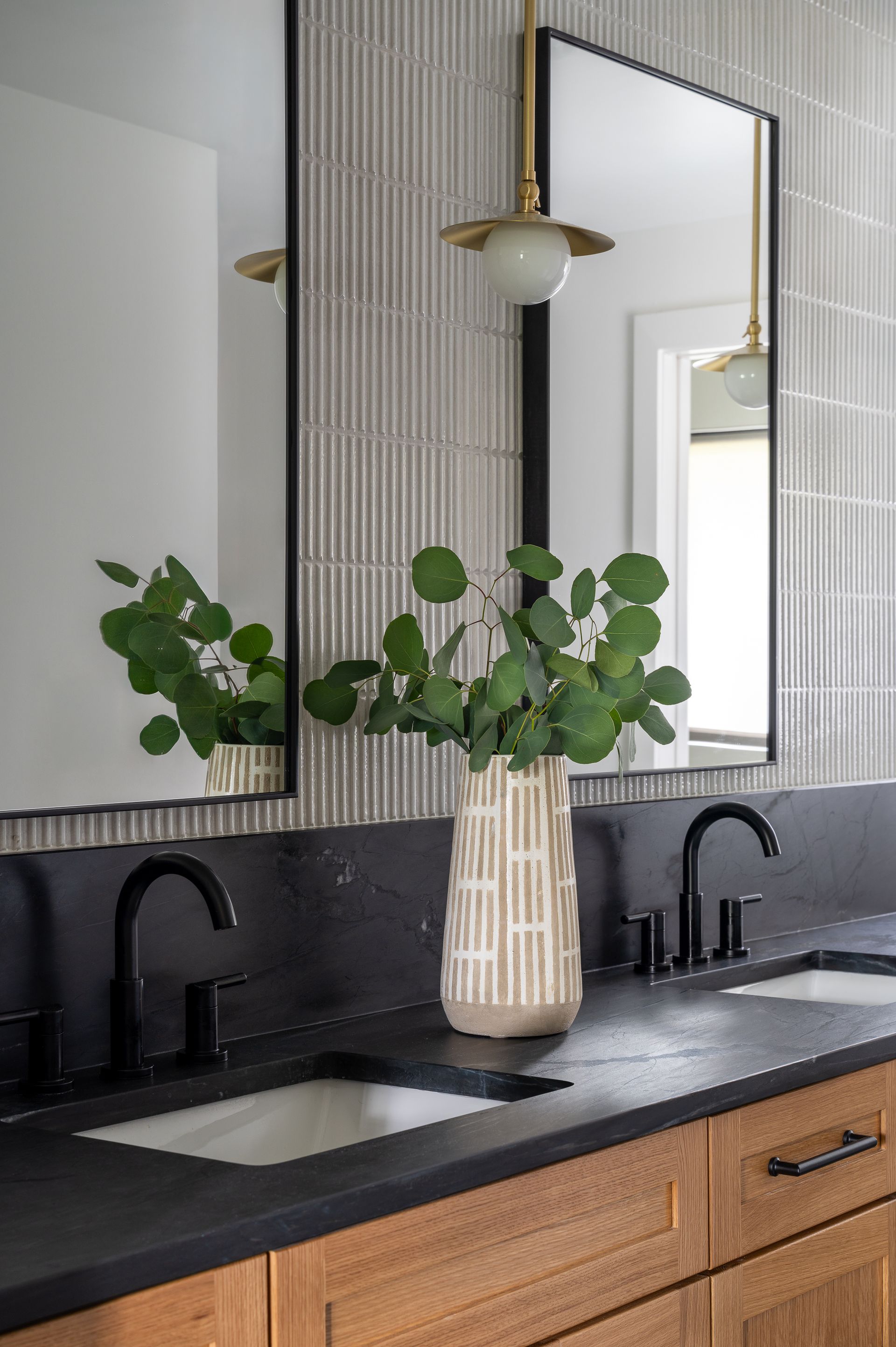 A bathroom with two sinks , two mirrors , and a vase of plants on the counter in Seattle, WA.