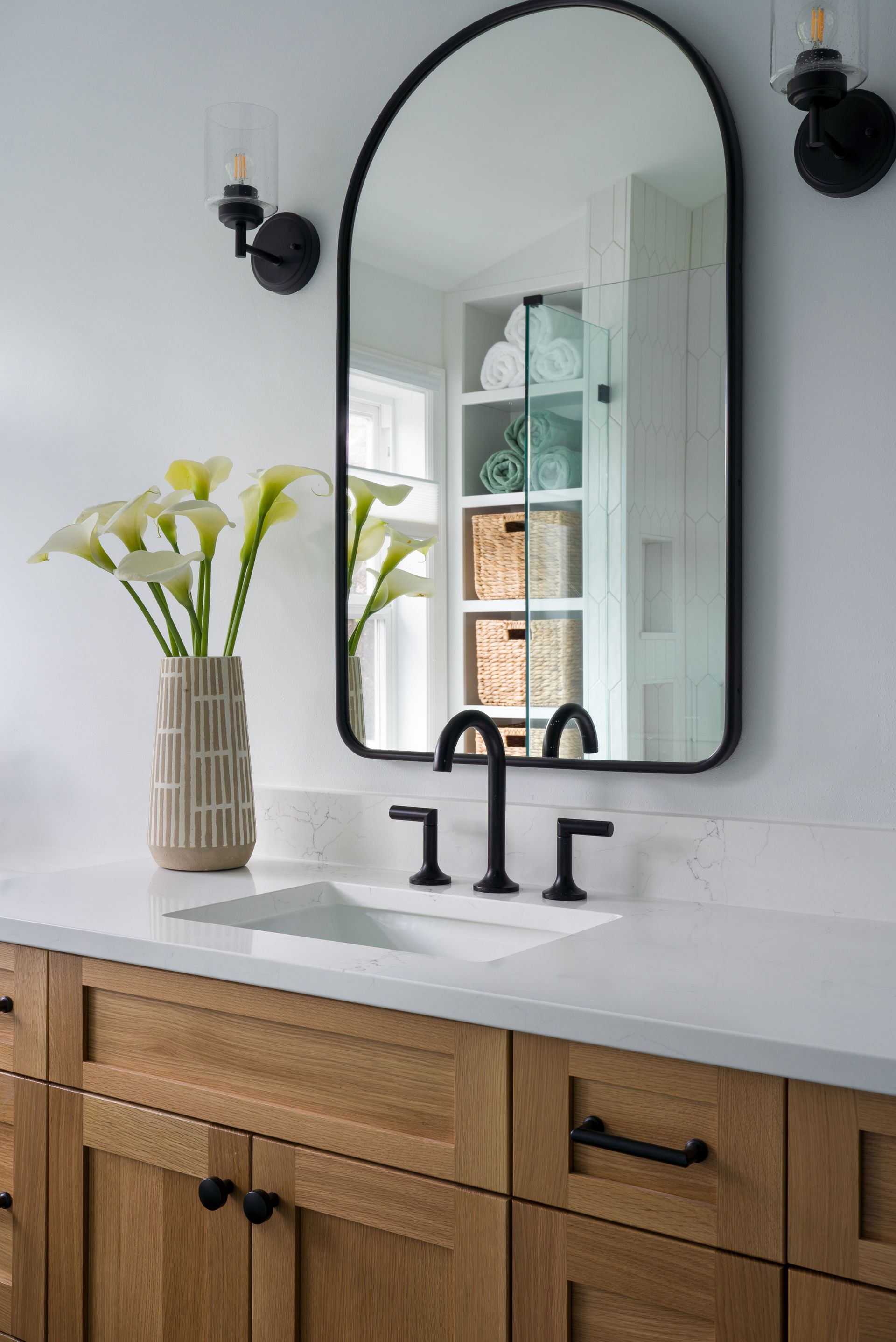 A bathroom with a sink , mirror and vase of flowers.  Emily Barrows Photography. Design by Allison Myers Design.