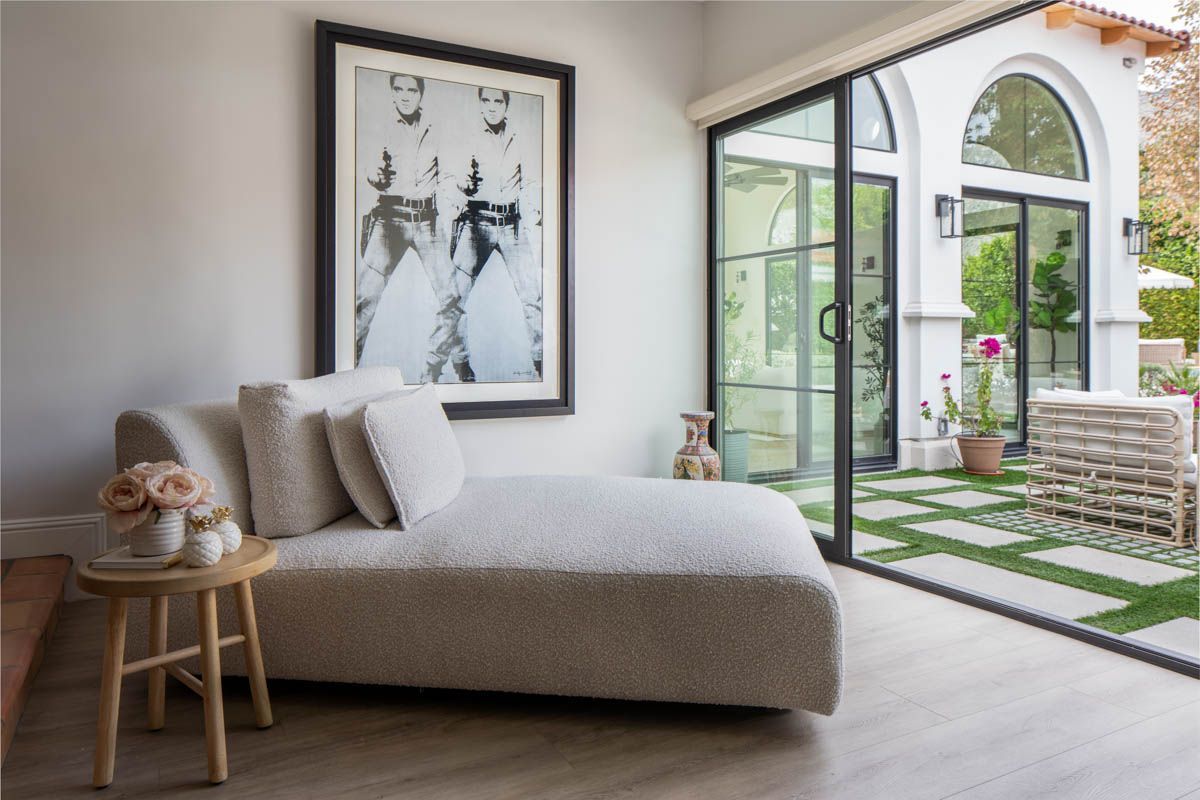A bedroom with a chaise lounge and a picture on the wall in Palm Springs, CA.  Photography by Emily Barrows Photography.