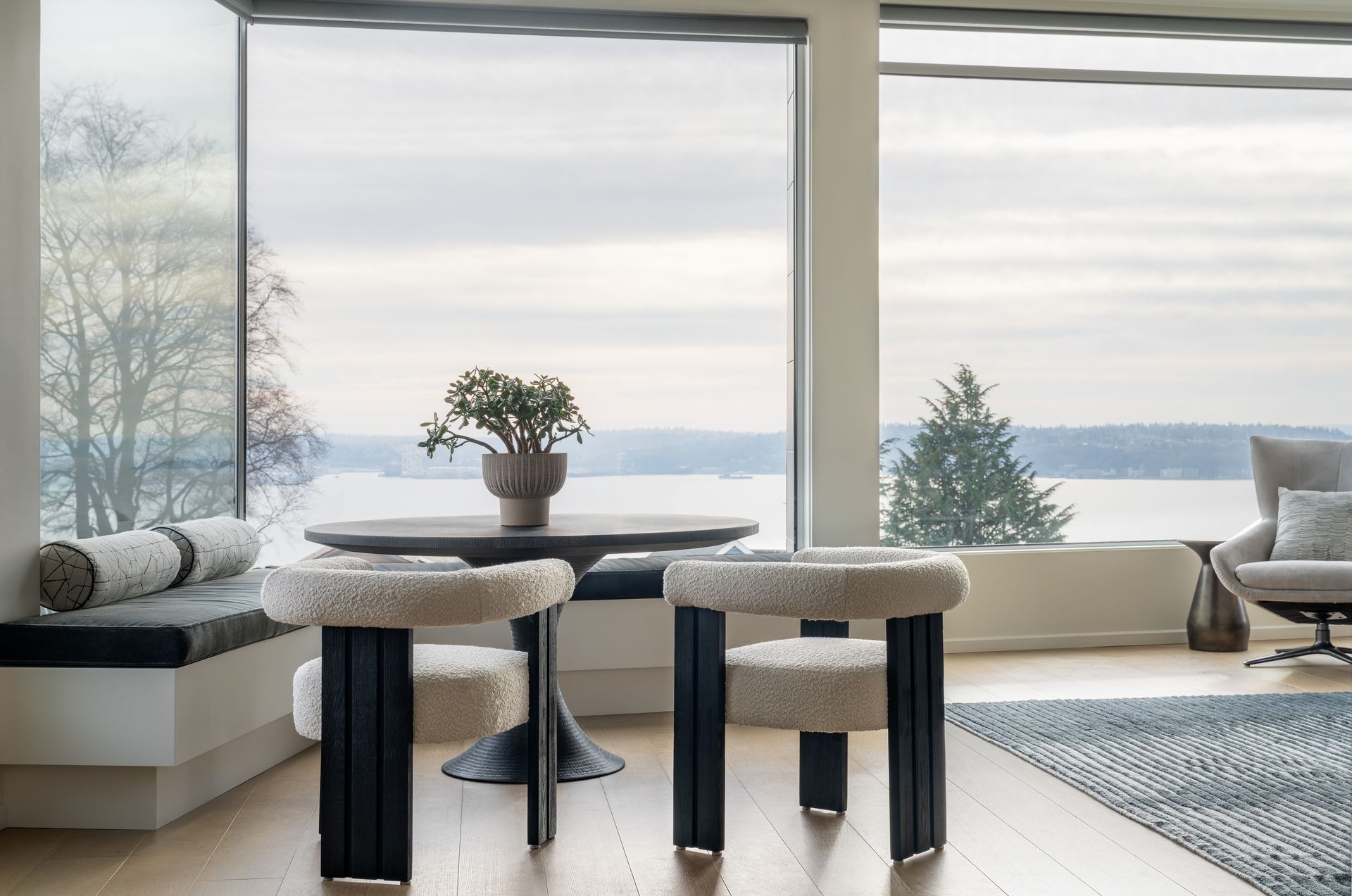A living room with a table and chairs in front of a large window facing Elliott Bay in Seattle, WA. 