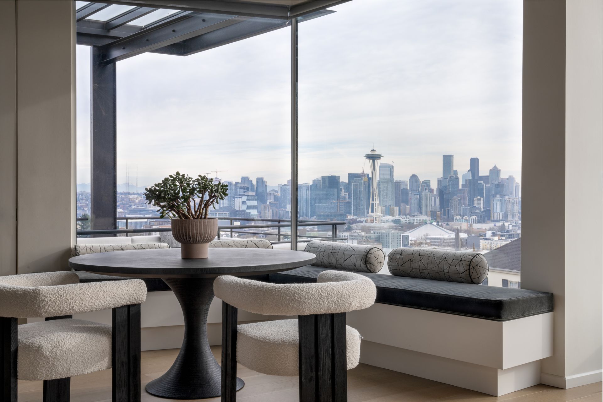 A dining room with a table and chairs and a view of the Seattle city skyline.  Photography by Emily Barrows Photography.
