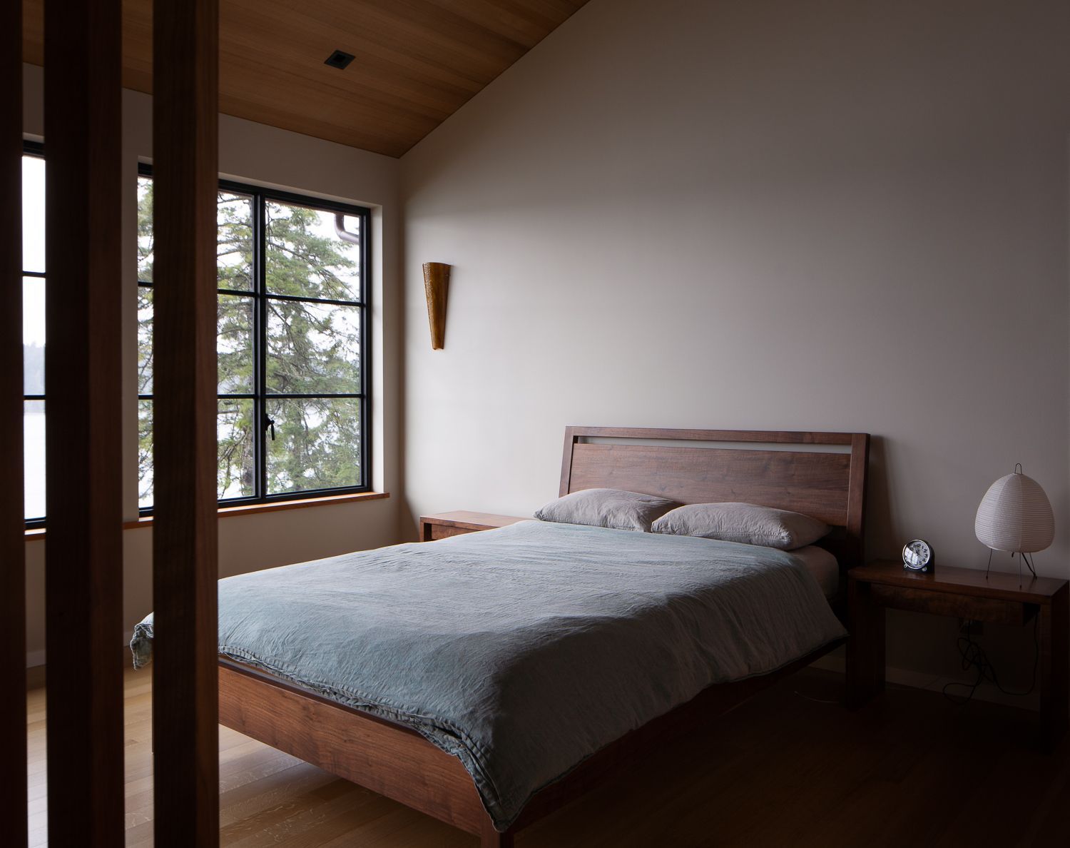 A bedroom with a large bed and a window. Bainbridge Island, WA. Emily Barrows Photography. Wenzlau Architects.