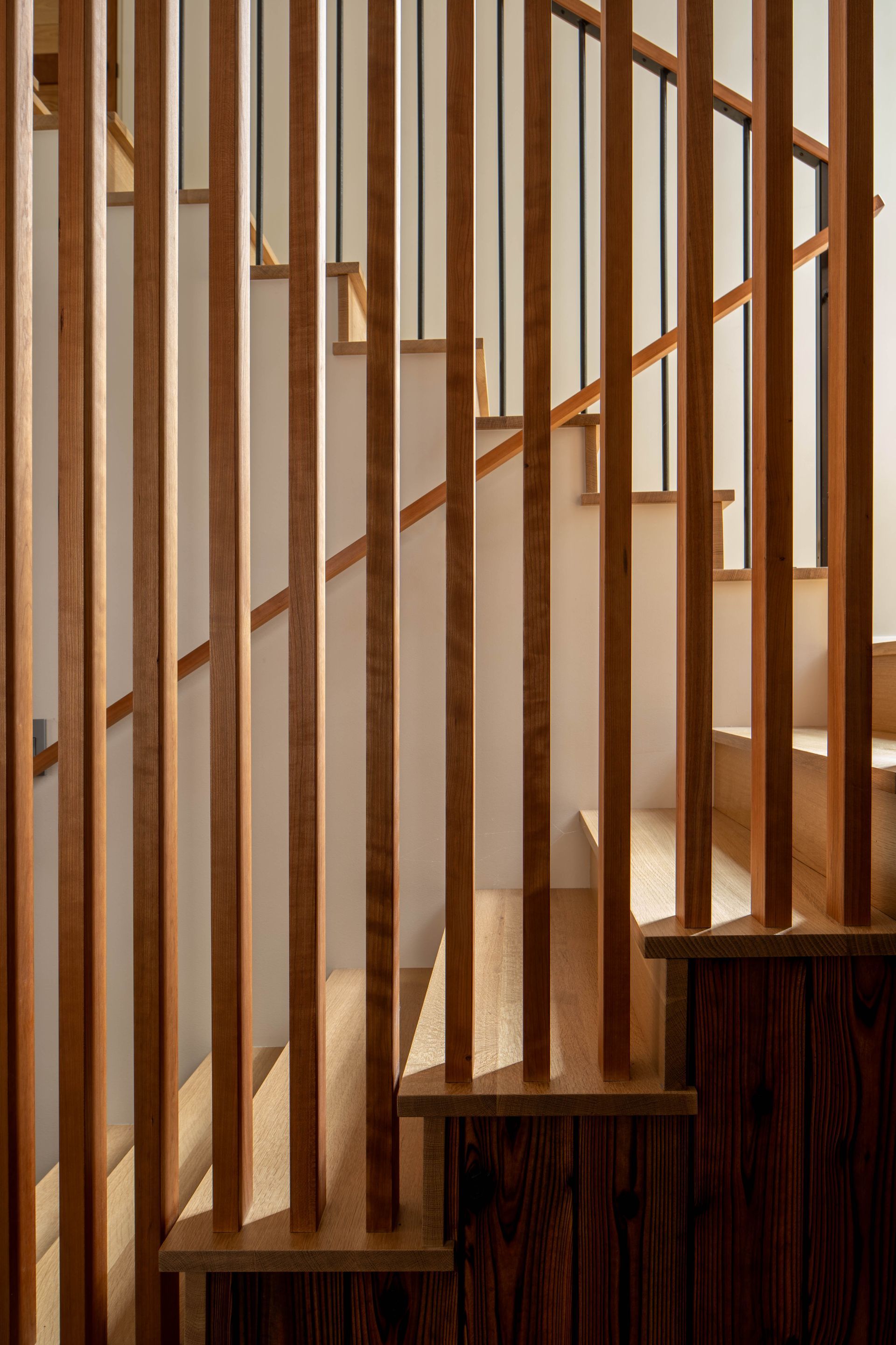 A wooden railing surrounds a set of stairs. Wenzlau Architects. Emily Barrows Photography. Bainbridge Island