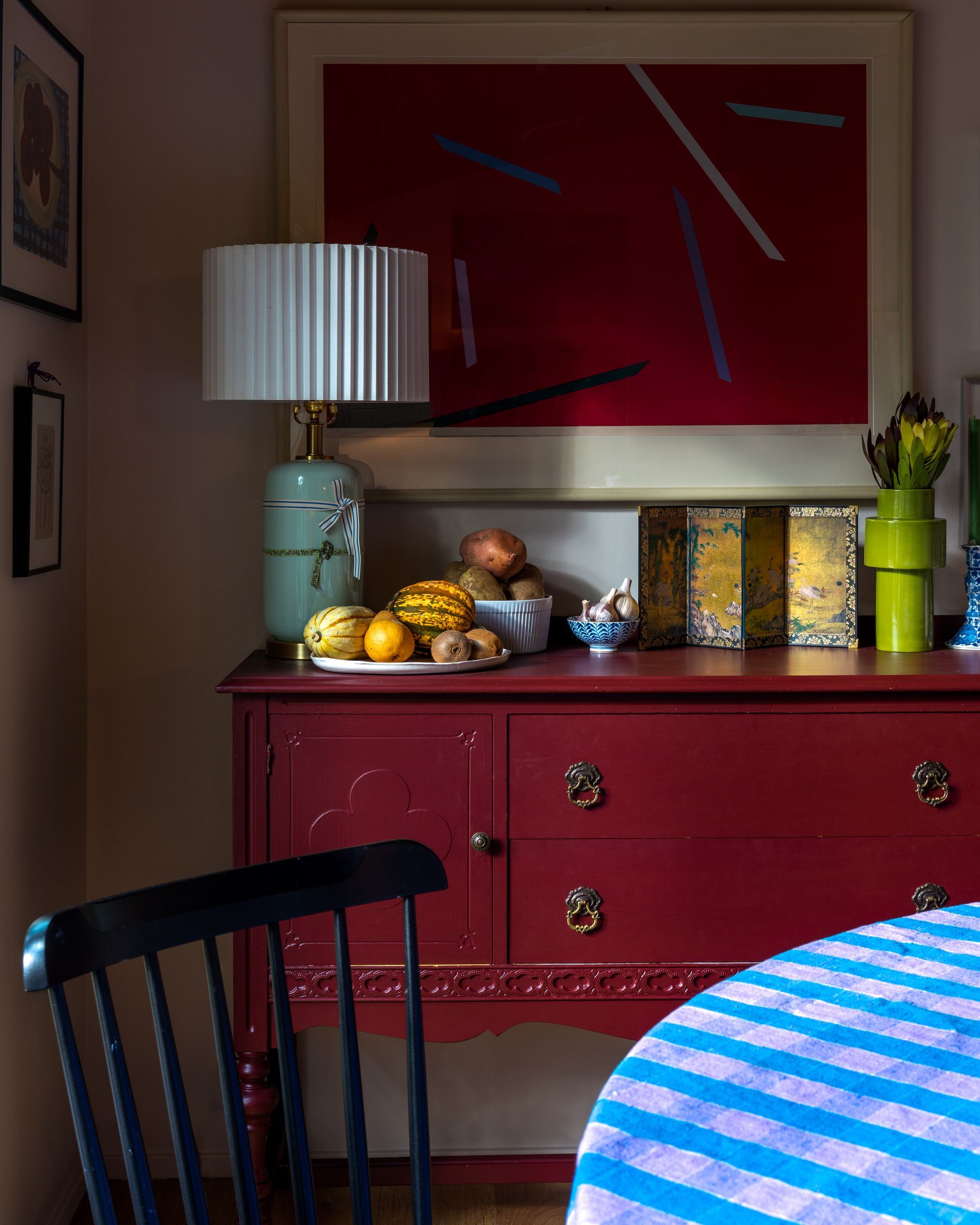 A red dresser with a lamp and fruit on it. Emily Barrows Photography