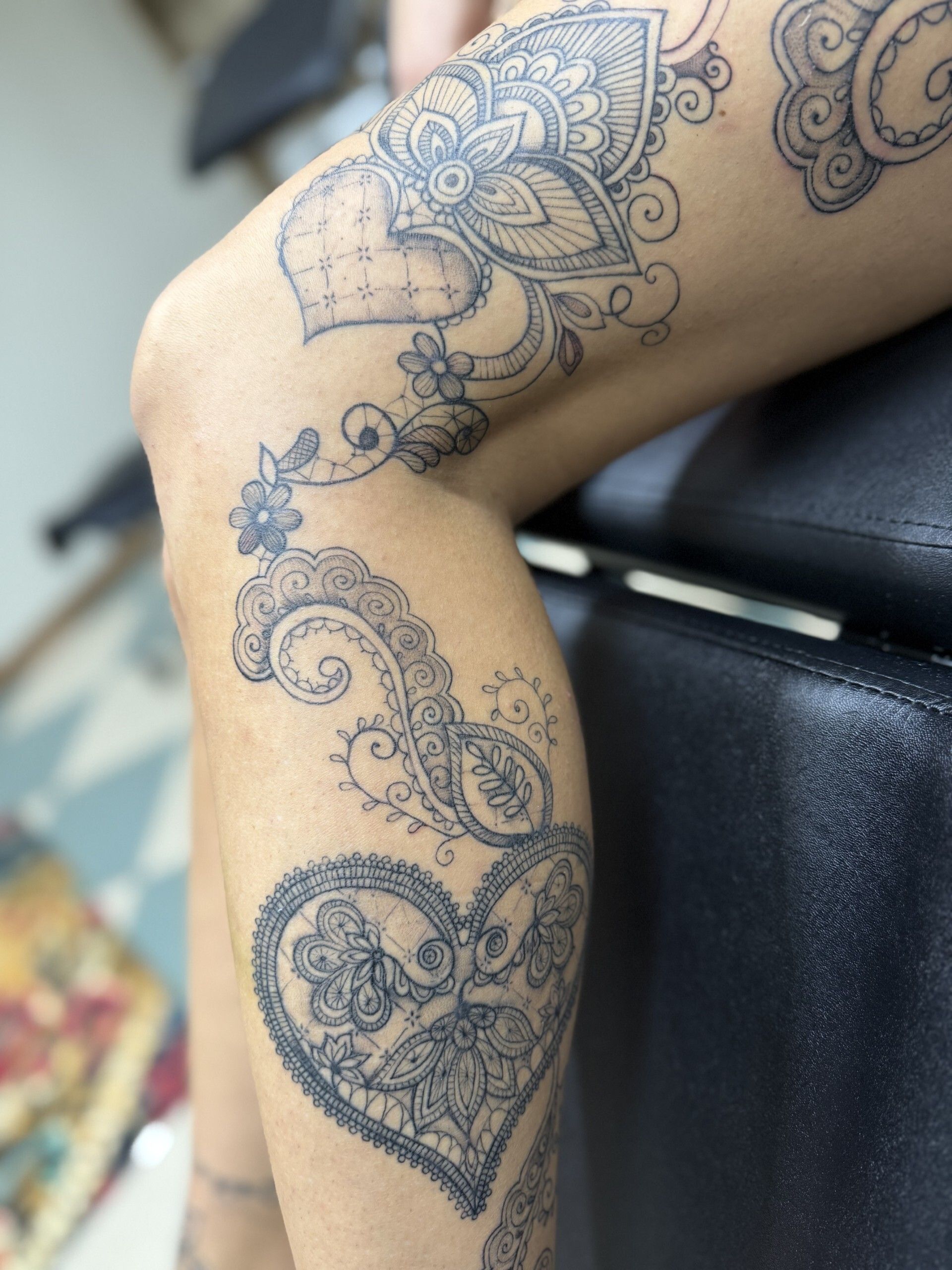 Gamba con tatuaggi floreali e a forma di cuore con motivo paisley.