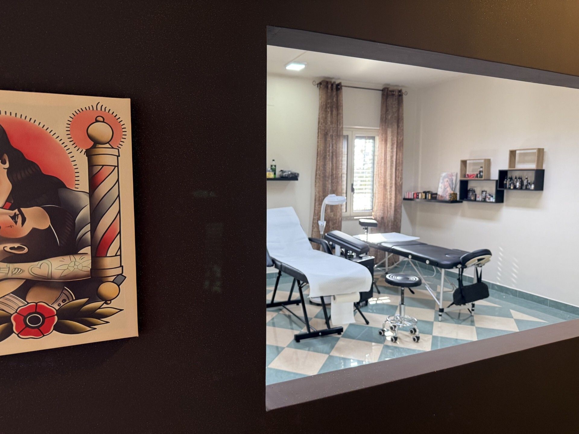 Interno di uno studio di tatuaggi con due lettini per tatuaggi e un disegno incorniciato sulla parete.