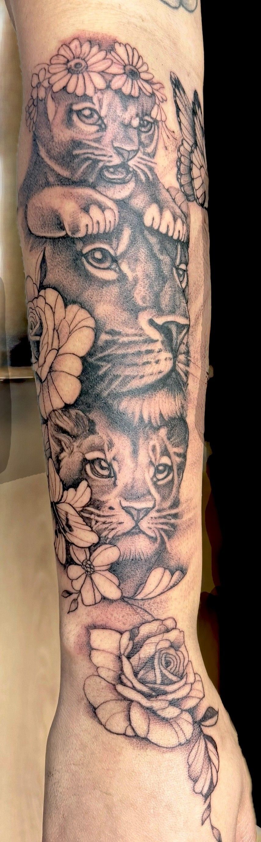 Tatuaggio di un garofano nero e grigio sull'avambraccio di una persona, con gambo e bocciolo.