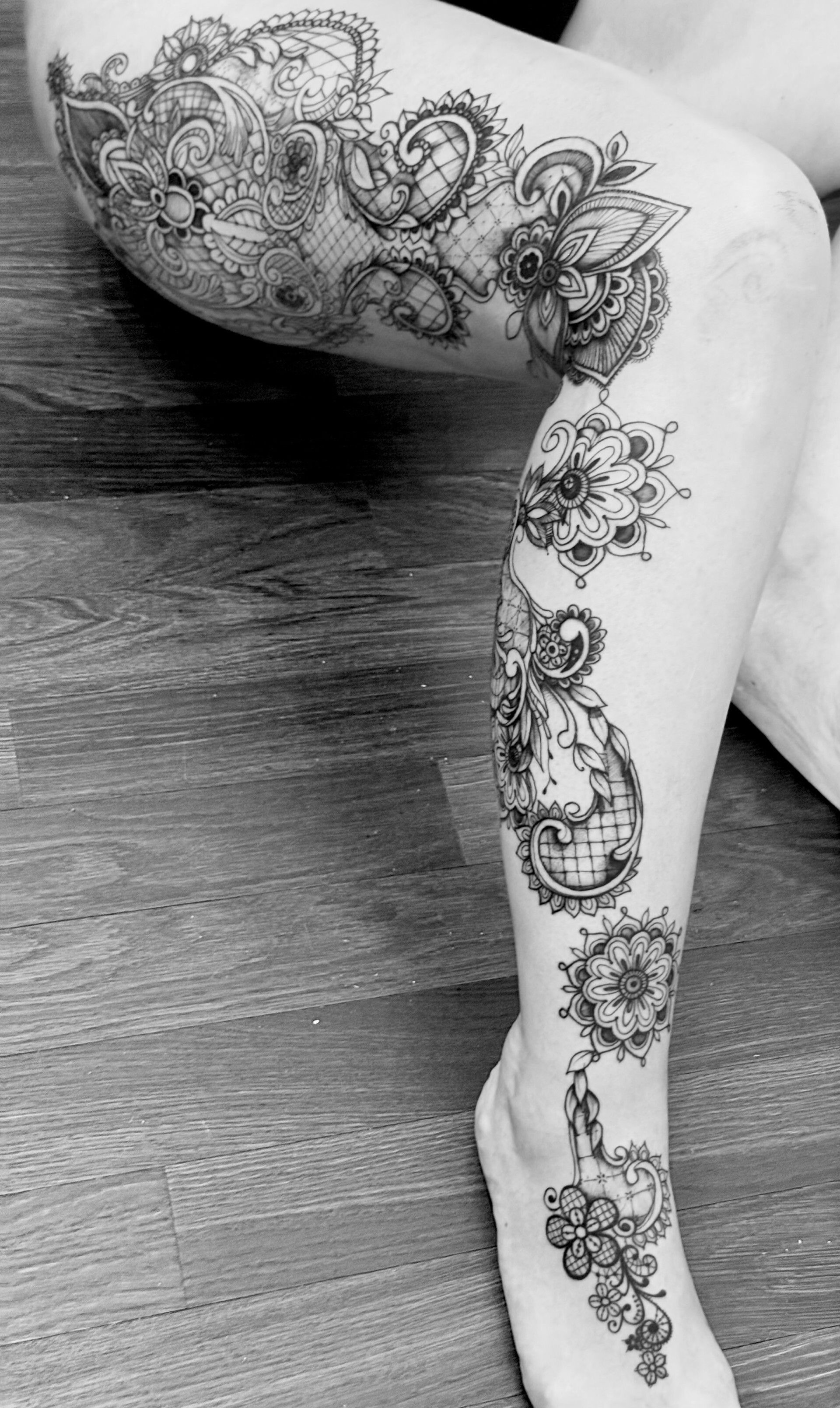 Foto in bianco e nero di una gamba ricoperta di tatuaggi intricati