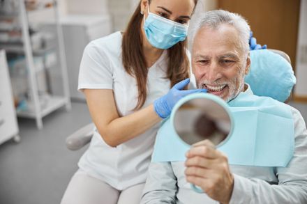 dental patient smiling into mirror after getting crowns and bridges | Waterford MI