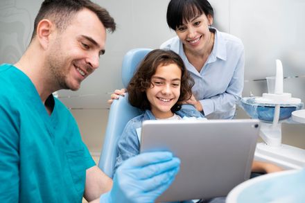 Dentist and staff looking at xrays and smiling | general dentist in Waterford MI