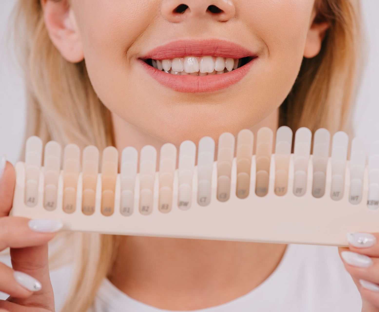 woman holding shades of teeth whitening | Best dentist in Waterford MI