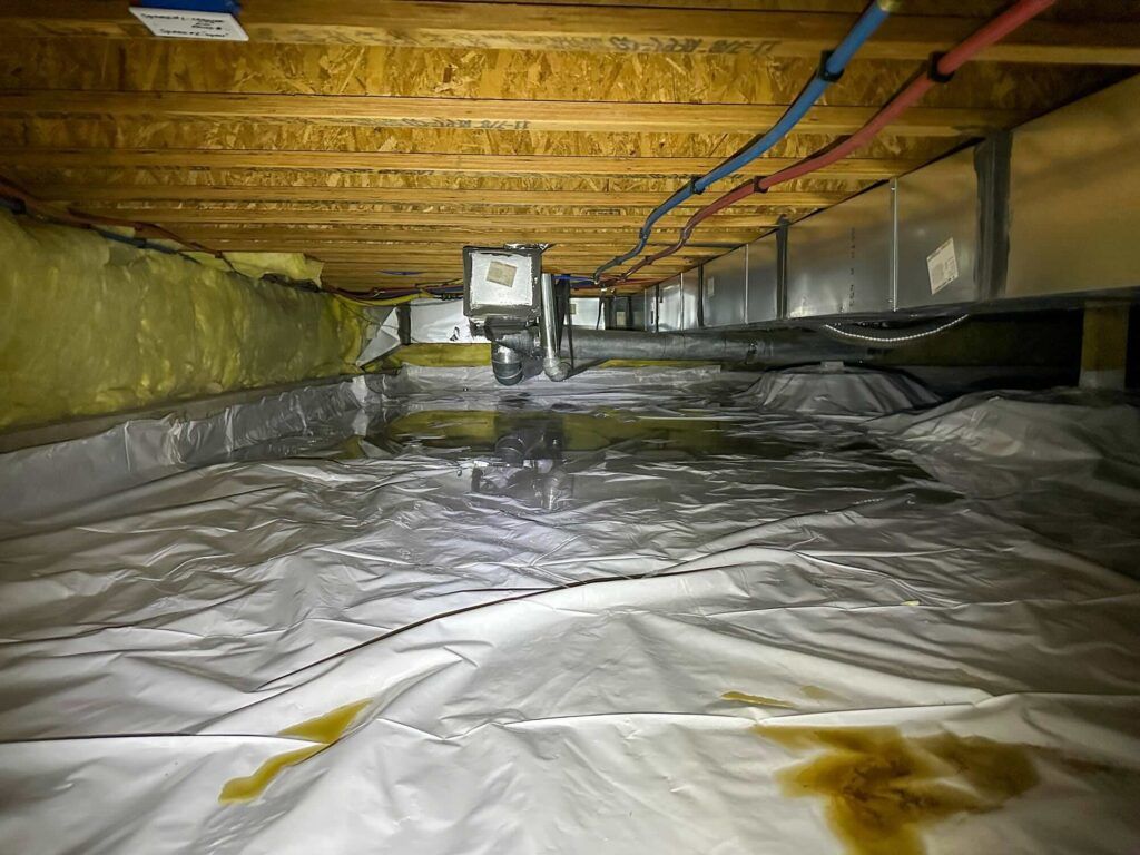 Insulated ductwork running through a construction area, silver and gray, supported by vertical posts.