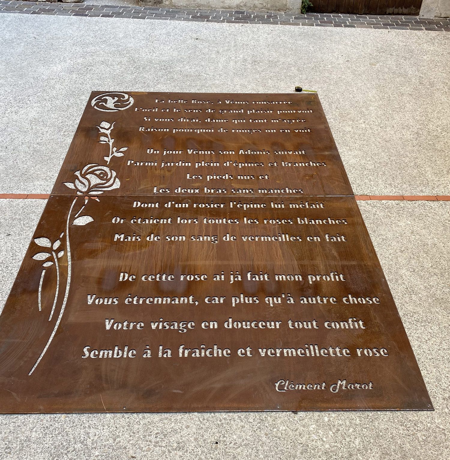 plaque au sol en acier corten avec inscription d'un poème