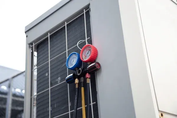 HVAC unit with gauges attached, showing blue and red pressure readings.