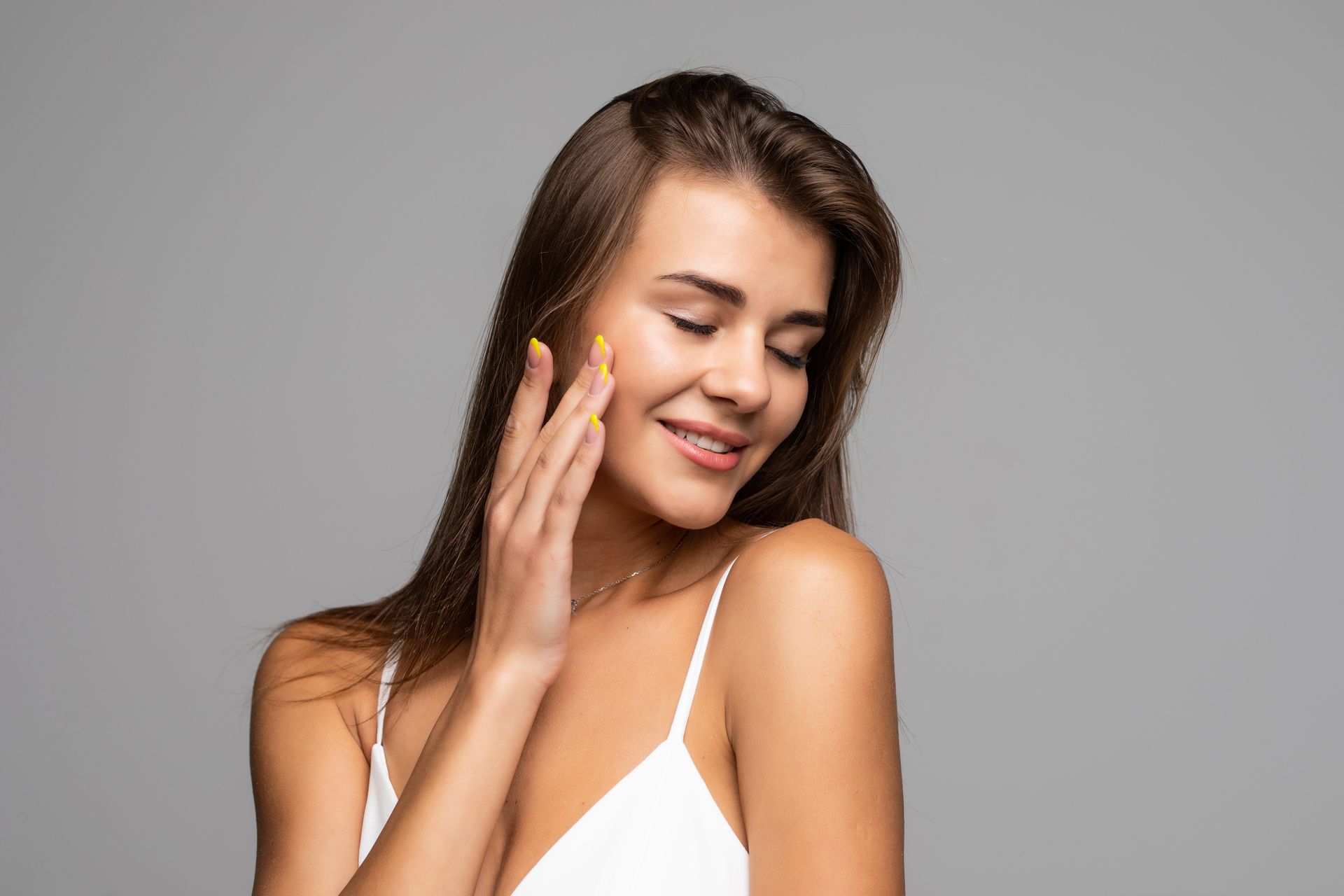 A woman is touching her face with her hand and smiling.