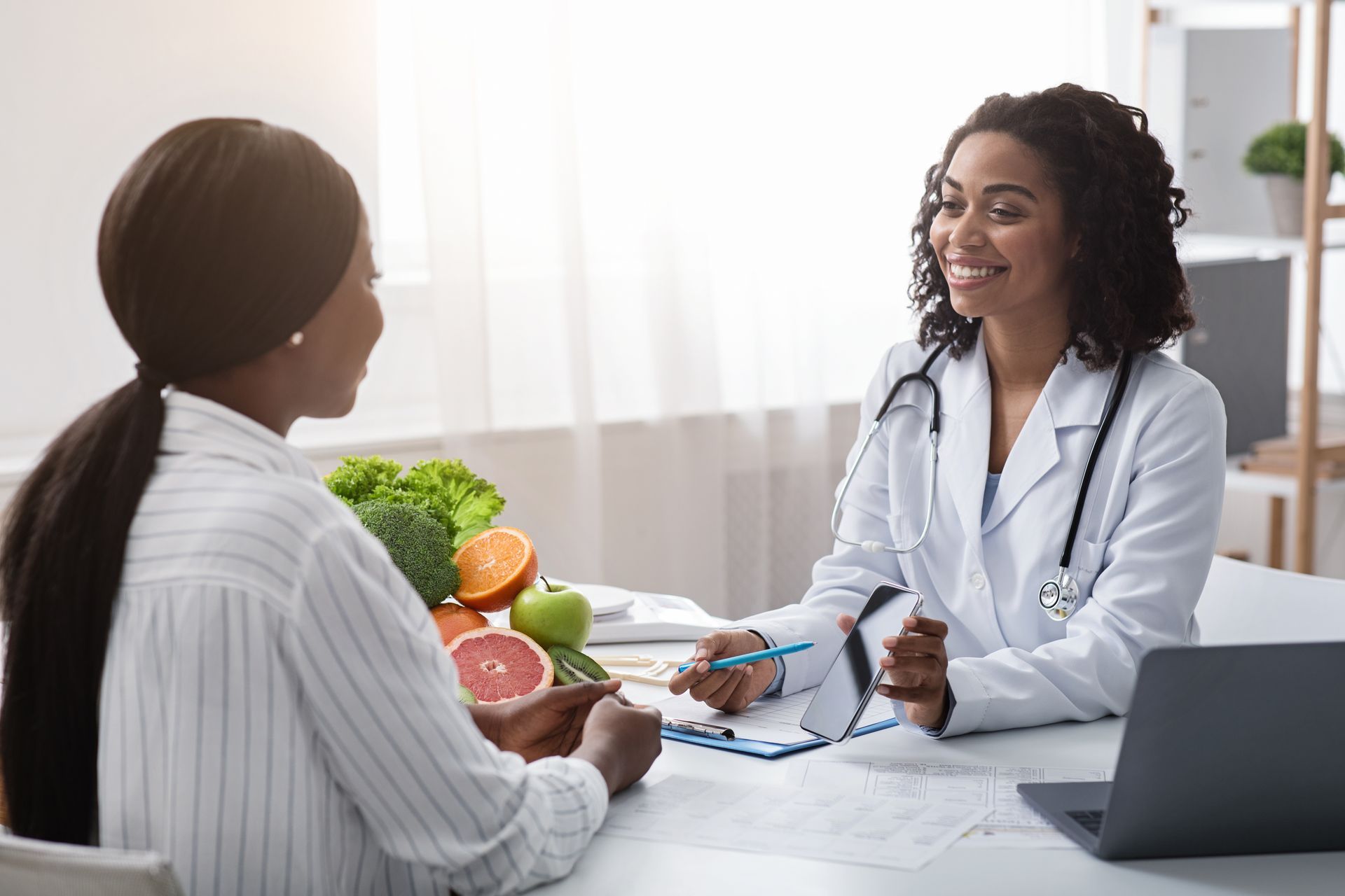 Dietitian smiling, consulting with a patient, vegetables on table.