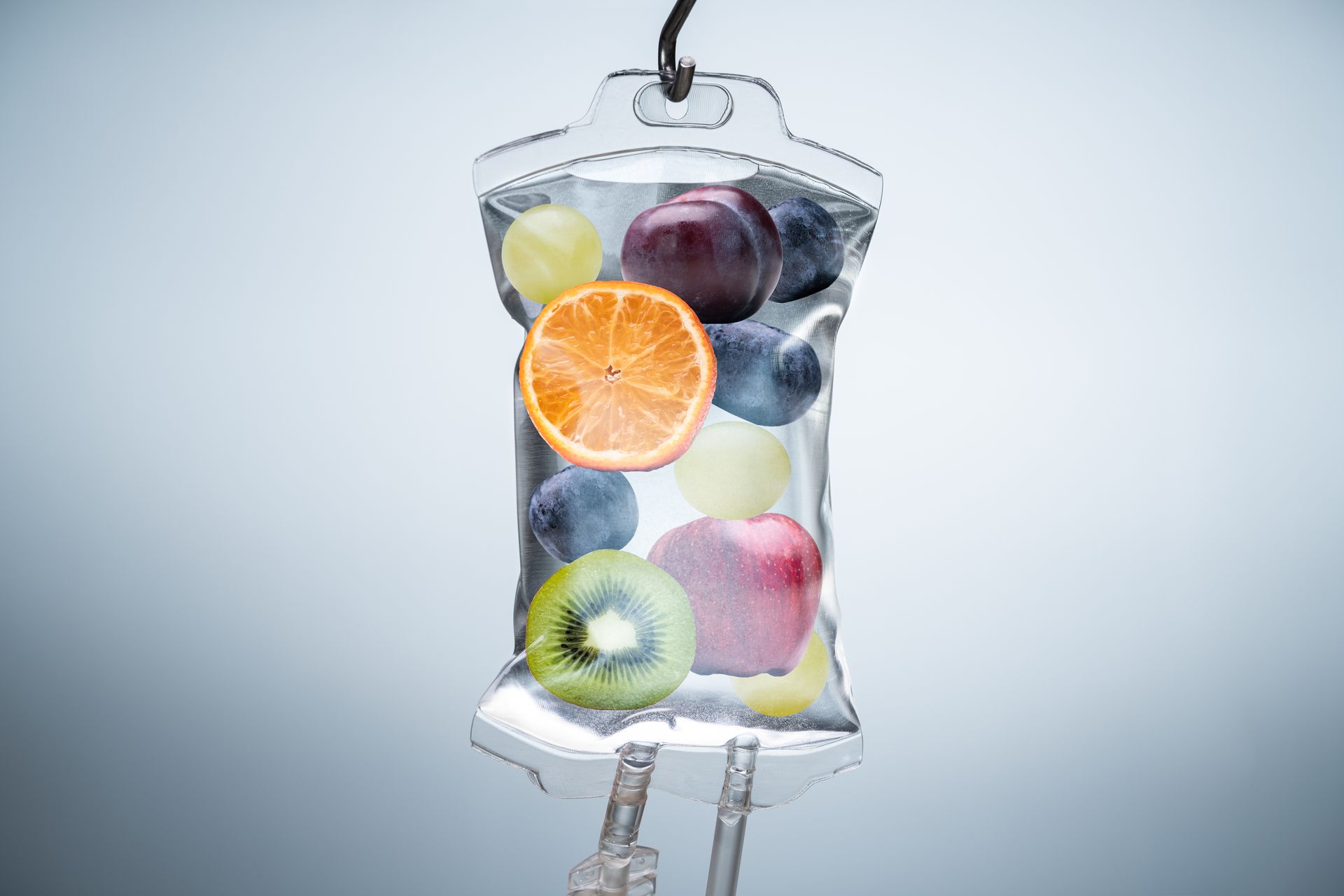 IV bag filled with various fruits: orange, kiwi, grapes, apple, and blueberries.